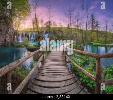Waterfall and wooden path in green forest in Plitvice Lakes Stock Photo