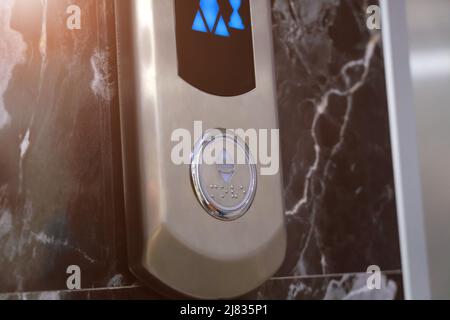 Close-up of the elevator call button up and down with braille. Arrow shows the lift going up Stock Photo