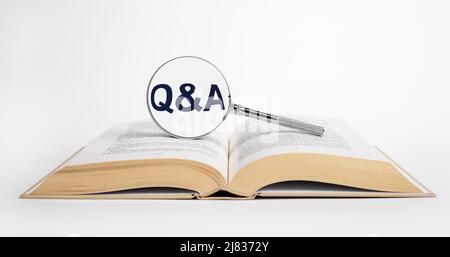 Search for answers to questions in books. Magnifying glass with qa abbreviation. Reading as source of knowledge concept. Open dictionary, textbook, code or novel. High quality photo Stock Photo