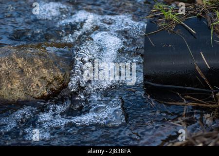 Water coming out of a pipe, and hitting a rock. Stock Photo