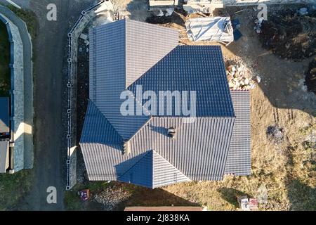 Chimney on house roof top covered with metallic shingles under construction. Tiled covering of building. Real estate development Stock Photo