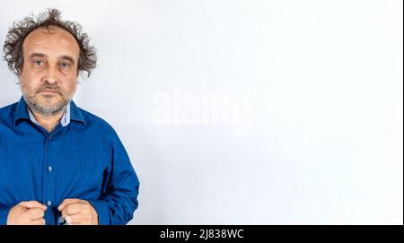 angry or confused looking man mad scientist type with blue man shirt and wild hair against light white background Stock Photo