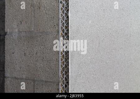 Concrete Brick wall, half raw and half with stucco and vinyl corner beading, separated by a vertical line. Stock Photo