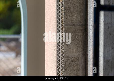 partially finished exterior wall with painted stucco exposing the exterior unfinished wall with corner beading and cinder concrete blocks. Stock Photo
