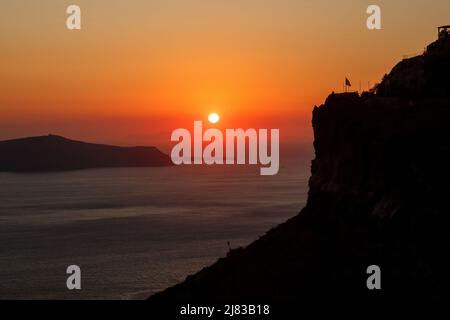 Sunset over Aegean sea and rock on Santorini island, Greece Stock Photo