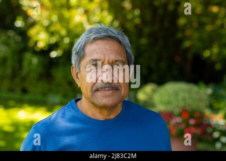 Close-up portrait of confident biracial senior man wearing sports clothing against plants in yard Stock Photo