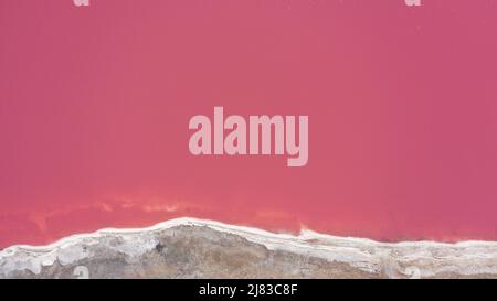 Flying over a pink salt lake. Salt production facilities saline evaporation pond fields in the salty lake. Dunaliella salina impart a red, pink water Stock Photo