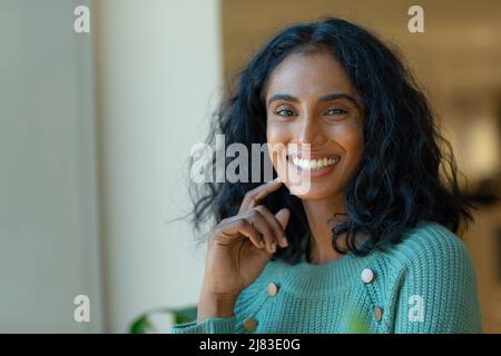 Portrait of smiling beautiful young biracial businesswoman with black hair at workplace Stock Photo