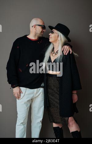 Vertical medium long studio shot of mature Caucasian man and woman in love wearing stylish clothes looking at each other Stock Photo