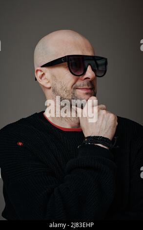 Vertical medium close-up studio portrait of confident stylish mature Caucasian man wearing sunglasses looking away Stock Photo