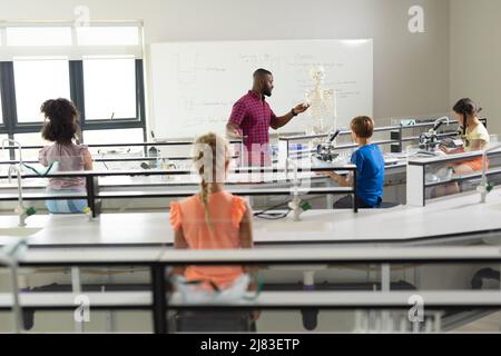 African american young male teacher explaining skeleton to multiracial students in laboratory Stock Photo