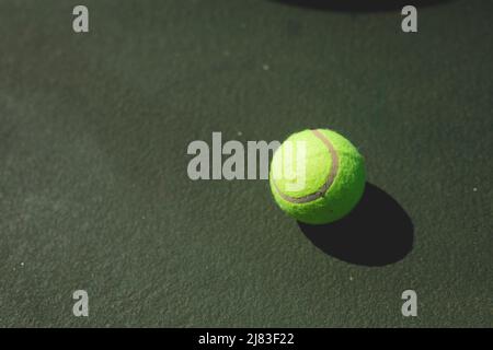 Directly above view of green tennis ball with shadow on gray court during sunny day Stock Photo