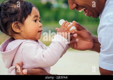 happy family applying hand-sanitizer anti-bacterial gel to daughter hands Stock Photo