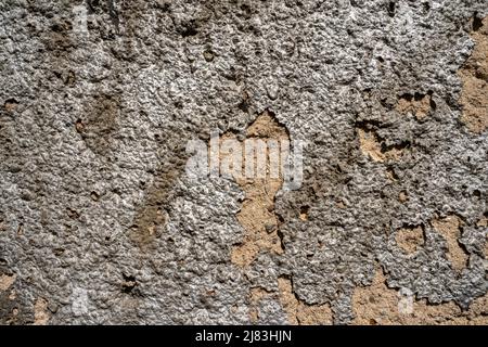 A very brittle wall, where the plaster is crumbling off and gets a very metallic look when the sun hits it. Stock Photo