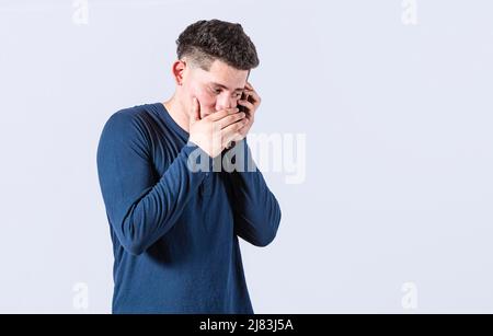 Man secretly talking on the phone, on an isolated background. Man talking on the phone covering his mouth, young man secretly talking on the phone Stock Photo