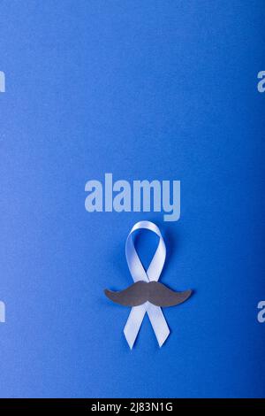 Directly above shot of prostate cancer awareness blue ribbon with paper mustache on blue background Stock Photo