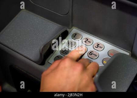 Hand at an ATM, entering the PIN, withdrawing money Stock Photo