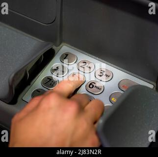 Hand at an ATM, entering the PIN, withdrawing money Stock Photo