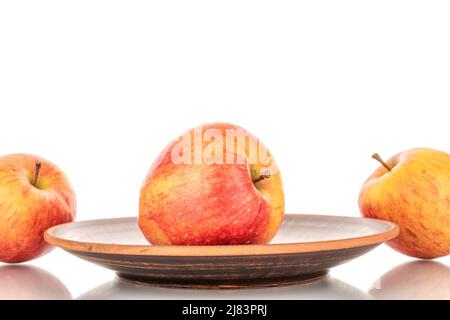 Three juicy organic apples with a clay dish, close-up, isolated on a white background. Stock Photo