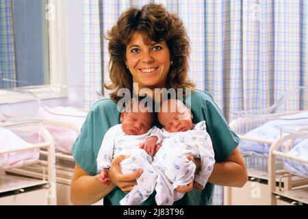 1980s SMILING MATERNITY NURSE LOOKING AT CAMERA HOLDING NEWBORN AFRICAN-AMERICAN TWIN BOYS IN HOSPITAL  - km9424 NET002 HARS NOSTALGIA NURSES OLD FASHION 1 JUVENILE WELCOME BALANCE NURSING INFANT TWIN IDENTICAL DOUBLE PLEASED JOY LIFESTYLE FEMALES HEALTHINESS HOME LIFE COPY SPACE LADIES PERSONS INSPIRATION MATCH CARING MALES EYE CONTACT HEALTHCARE MATCHING SAME SUCCESS OCCUPATION HAPPINESS PROVIDER CHEERFUL PROVIDERS PRACTITIONERS HEALING AFRICAN-AMERICANS AFRICAN-AMERICAN BLACK ETHNICITY MATERNITY PRIDE HEALTH CARE OCCUPATIONS SIBLING SMILES HEALER JOYFUL PRACTITIONER BABY BOY LOOK-ALIKE Stock Photo