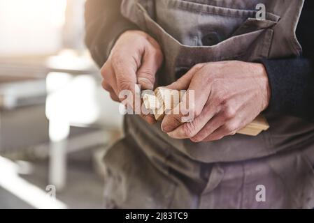 Quality is not an act. It is a habit. Carpenter using chisel to carve wood in workshop Stock Photo