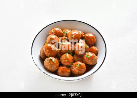 Meatballs with tomato sauce in bowl over white stone background. Close up view Stock Photo