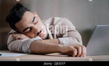Sleepy unproductive man office male worker businessman falling asleep at office desk tired multiracial student closed eyes feeling exhausted after Stock Photo