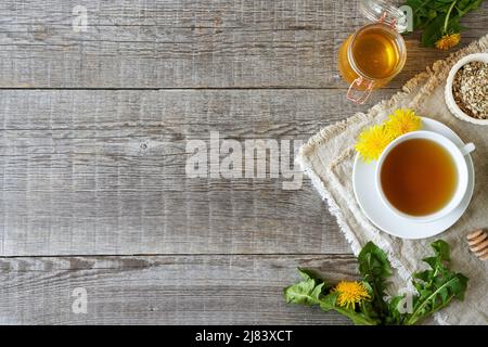 Dandelion tea, honey, bloomijng plant and dried root on a wooden background with copy space Stock Photo