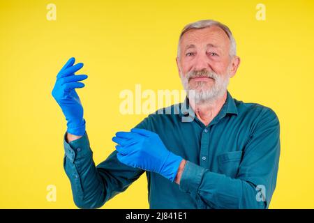 Portrait of a man with towel and spray ready to clean windows in studio yellow background Stock Photo