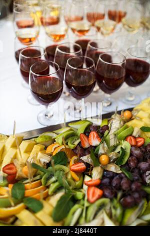 Assorted fruits and rows of glasses with wine Stock Photo