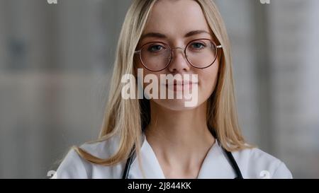 Caucasian female doctor wear eyeglasses make online video call in hospital clinic consult patient remote distant conversation. Medical assistant Stock Photo