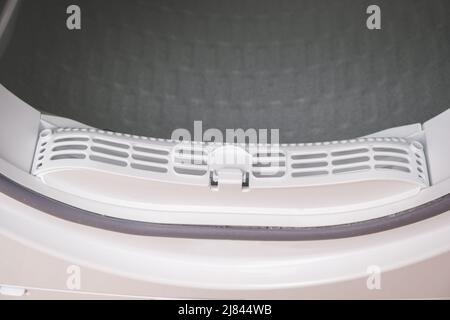 A man takes a lint filter out of the dryer and cleans it from dust, lint, hair, wool. Stock Photo