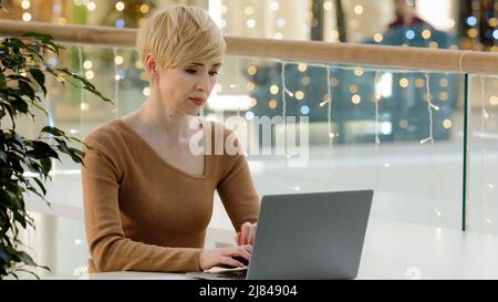 Middle aged adult business woman lawyer worker 40s lady with laptop working typing chatting consultation online writing report online professional Stock Photo
