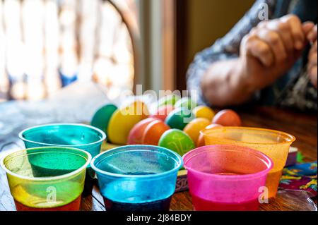 Plastic cups for dying Easter eggs with finish carton in the background. Stock Photo
