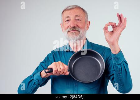 man old holding frying metal non-stick pan in studio white background Stock Photo