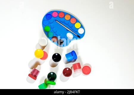 Jars with gouache multicolored paint, palette, brush. Top view.Flat lay. Stock Photo