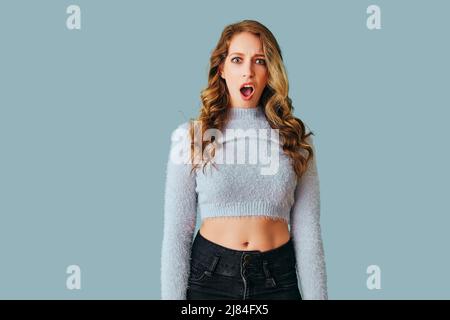 portrait of young adult shocked woman with long curly hair looking at camera studio Stock Photo