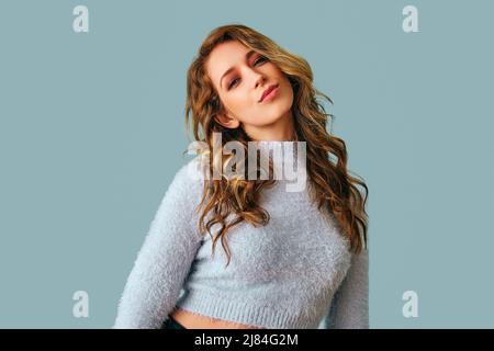 portrait of beautiful young woman with long curly hair looking at camera studio Stock Photo