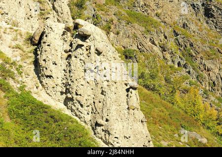 Unusual layered stone formations on the slope of a high mountain overgrown with grass. Stone mushrooms, Altai, Siberia, Russia. Stock Photo