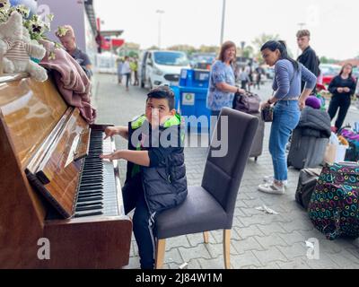 Przemysl, Poland. 12th May, 2022. A Ukrainian refugee boy plays the piano at Tesco Humanitarian aid processing center in Przemysl, Poland, near the Medyka Border. (Credit Image: © Amy Katz/ZUMA Press Wire) Stock Photo