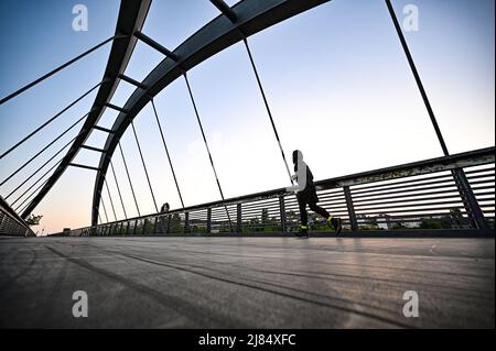 Berlin, Germany. 13th May, 2022. A jogger runs across a bridge in the Berlin-Prenzlauer Berg district. Credit: Fabian Sommer/dpa/Alamy Live News Stock Photo