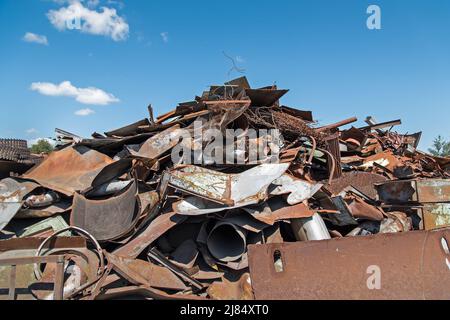 A pile of rusty scrap iron against the blue sky Stock Photo