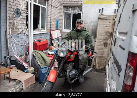 Mariupol, Ukraine. 12th Apr, 2022. A Donetsk People's Republic mobilization soldier poses with his rifle on a motorbike outside an impromptu field hospital near the Mariupol frontline. The battle between Russian/Pro Russian forces and the defencing Ukrainian forces lead by Azov battalion continues in the port city of Mariupol. Credit: SOPA Images Limited/Alamy Live News Stock Photo