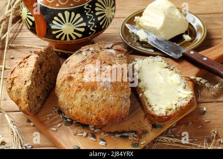 Butter on a piece of homemade bread on a wooden table Stock Photo