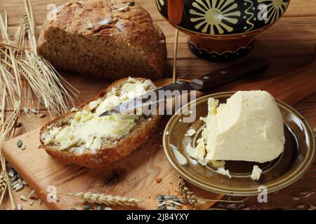 Butter on a piece of homemade bread on a wooden table Stock Photo