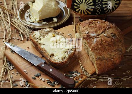 Butter on a piece of homemade bread on a wooden table Stock Photo