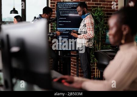 Programmers looking for source of cyber attacks and system security coverage. Software developer team members programming encryption applications to be used as security measure. Stock Photo