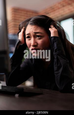 Worried asian network developer failed to create a security protocol for database. Stressed frustrated cybernetics engineer cannot bypass firewall system in order to restore encrypted files stability. Stock Photo