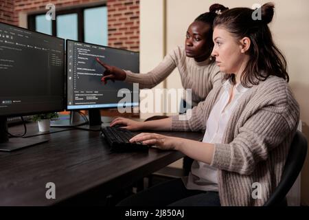 Blockchain engineer pointing out mistake in network security software line code. Cybernetics developers engineering system updates and processing data blocks uploaded by artificial intelligence. Stock Photo
