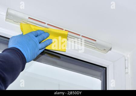 Man removing dirt from glass with squeegee. View of blue sky